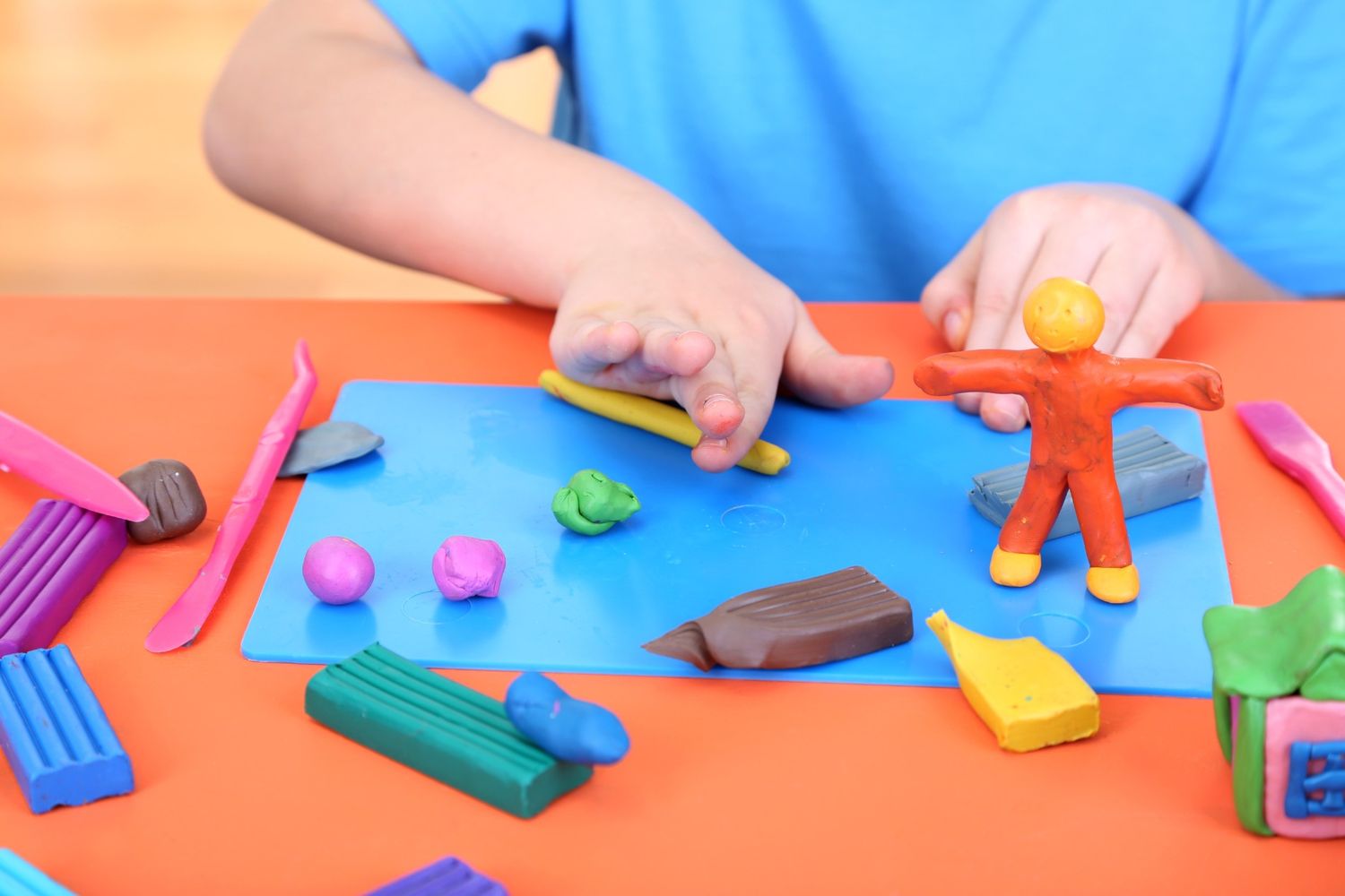 Child engaging in occupational therapy for children by building fine motor skills with colourful playdough during a therapy session.